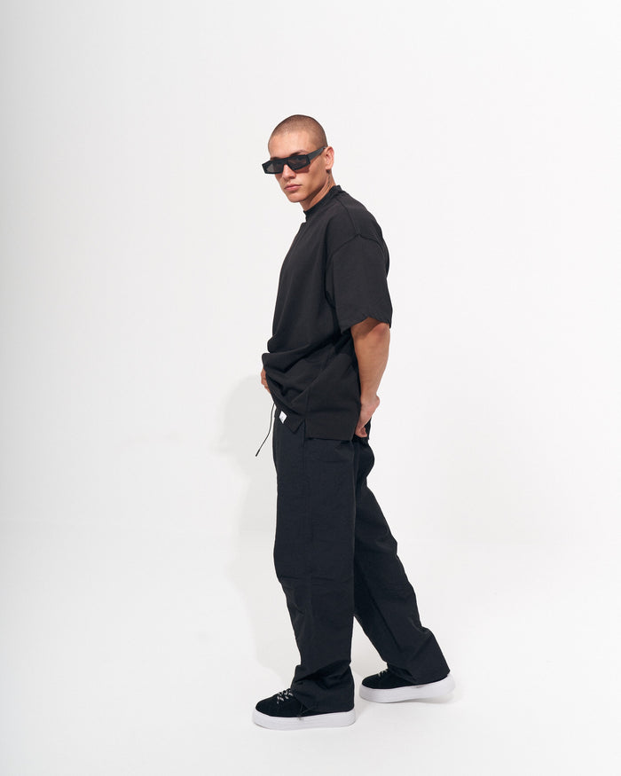 Martin Valen men's baggy pant in black, full-length side view on model with hands in pockets and relaxed leg
