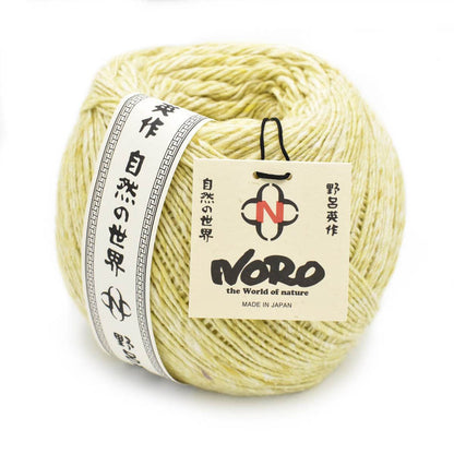 Close up of Noro Yarn in Moegi shade; Appears light yellow/green with white throughout; Shown from side with paper label wrapped around left outside edge in black and white with Japanese characters running up and down; Reads "NORO" "the World of nature" "MADE IN JAPAN" on tag tag attached with black tie on right side of yarn