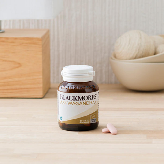 Blackmores Ashwagandha supplement bottle on a wooden surface with a neutral background.