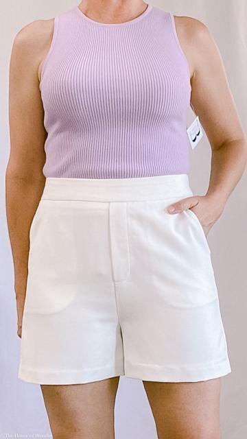 Woman wearing a lilac ribbed sleeveless top paired with tailored white front shorts