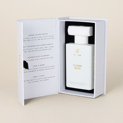 Front view of Clean Skin perfume bottle in open white presentation box showing gold logo on a beige background