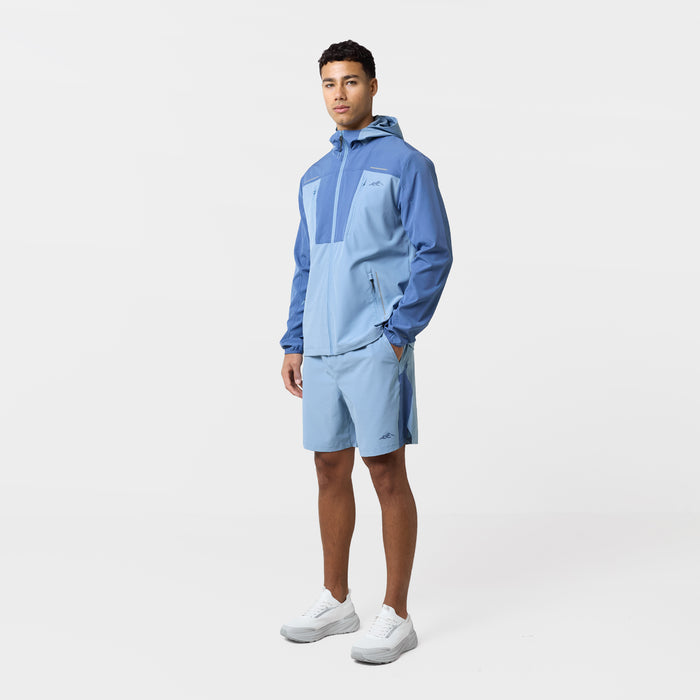The model is wearing the light blue tri-set featuring a hooded wind breaker and shorts