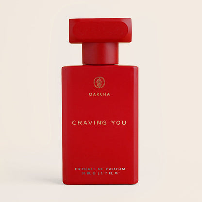 Front view of Craving You red perfume bottle showcasing matte rectangular bottle with gold logo on beige background