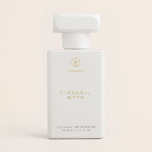 Front view of Ethereal Myth perfume bottle showcasing matte white rectangular bottle with gold logo and sculpted cap on pale beige background