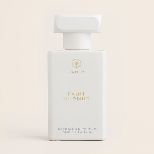 Front view of Faint Murmur 50ml perfume bottle with white body, gold Oakcha logo and square cap on pale beige background