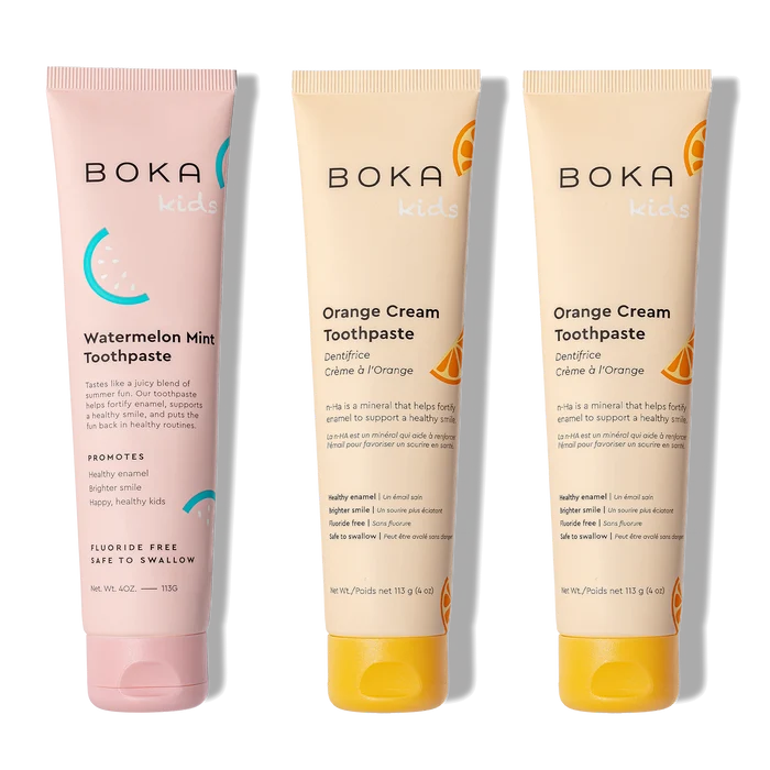 Three tubes of Boka toothpaste, two in orange cream flavor and one in watermelon mint flavor, on a white background.