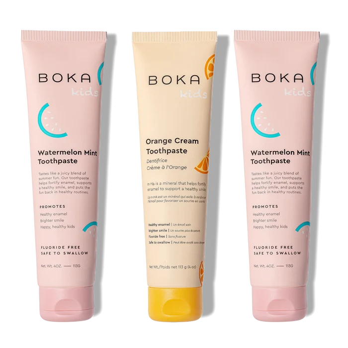 Three tubes of Boka toothpaste, two pink and one orange, on a white background.