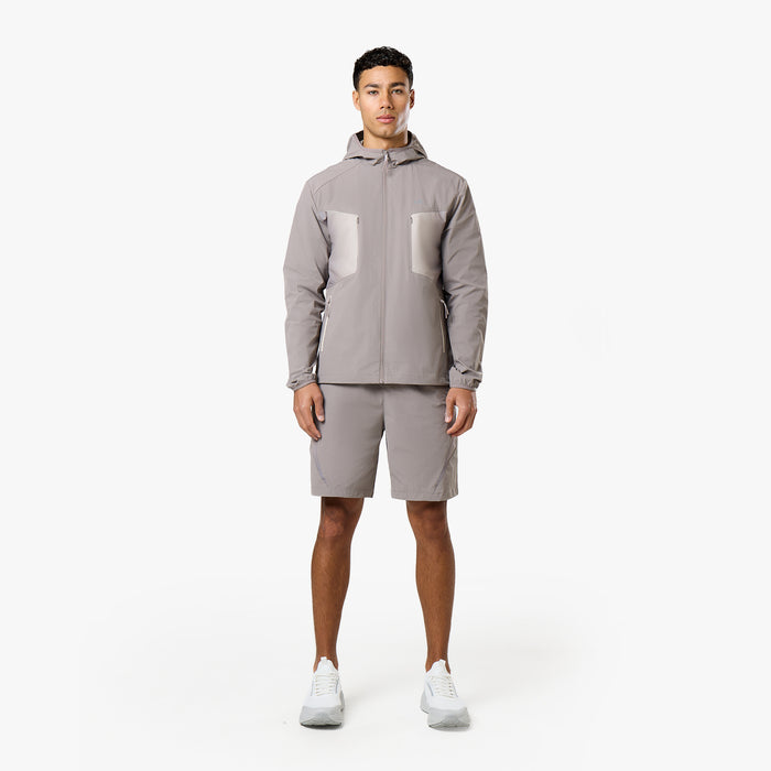 Model is wearing grey tri-set with hooded grey windbreaker with pockets and matching grey shorts