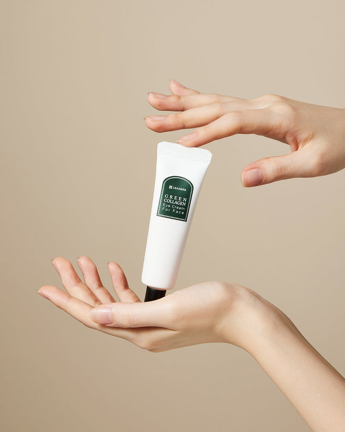 A tube of Green Collagen Eye Cream for Face | Leaders held delicately between two hands against a plain beige background, highlighting skincare and wellness care.