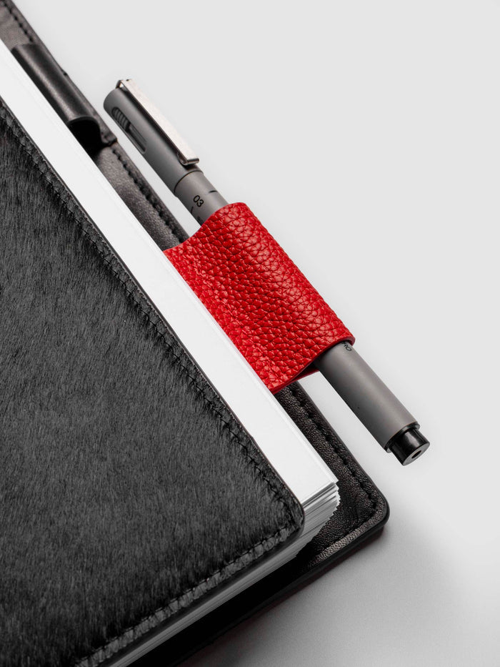 Rouge clip in use inside a black leather planner. A Uni Pin Marking Pen is placed inside the pen clip.