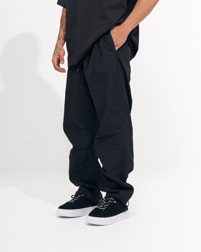 Martin Valen men's black baggy pant, side view with hand in pocket and wide relaxed leg