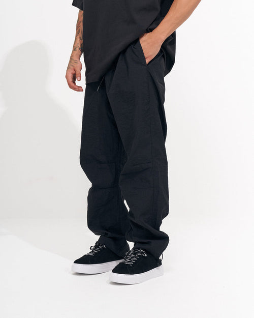 Martin Valen men's black baggy pant, side view with hand in pocket and wide relaxed leg