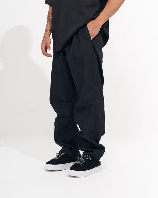Martin Valen men's black baggy pant, side view with hand in pocket and wide relaxed leg