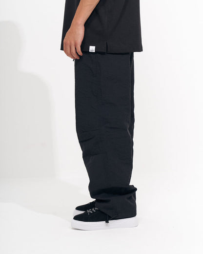 Martin Valen men's black baggy pant, close side view showing white logo tag at the hem