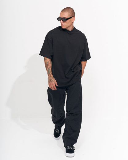 Martin Valen men's black baggy pant, rear view of model standing, loose fit with back of t-shirt and waistband visible