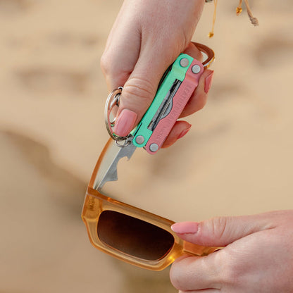 Person using the extra small screwdriver on a Leatherman Micra® in Bayside color to tighten sunglasses on the beach.