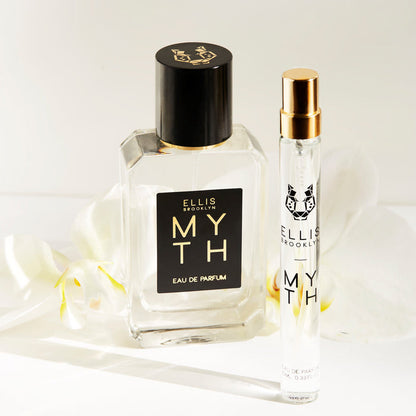 Myth 50ml Eau De Parfum and Myth 10ml Eau De Parfum Travel Spray in front of white flowers on white background.
