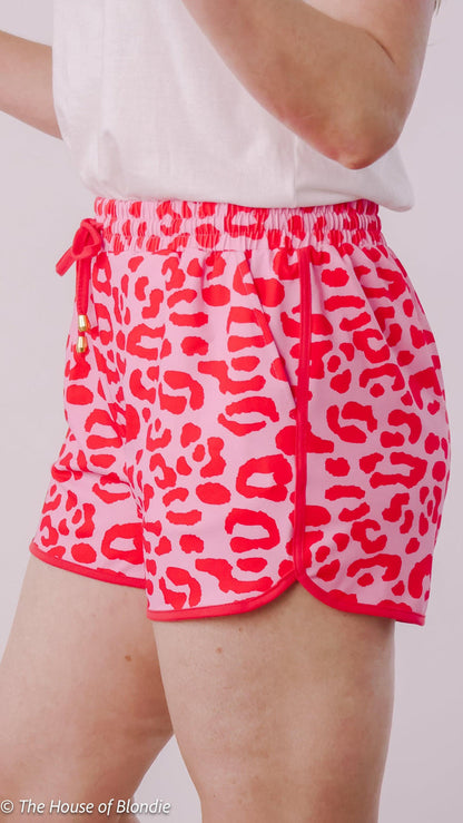 Close-up of pink and red leopard print knockabout shorts with drawstring waistband in women's boutique style
