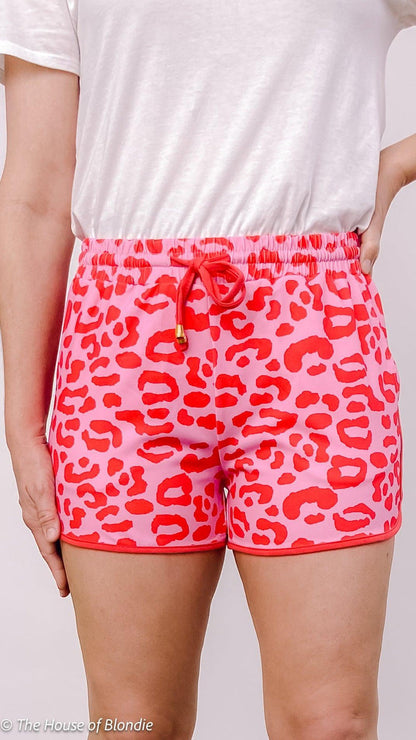 Close-up of women's pink and red leopard print shorts with drawstring waist styled with white top