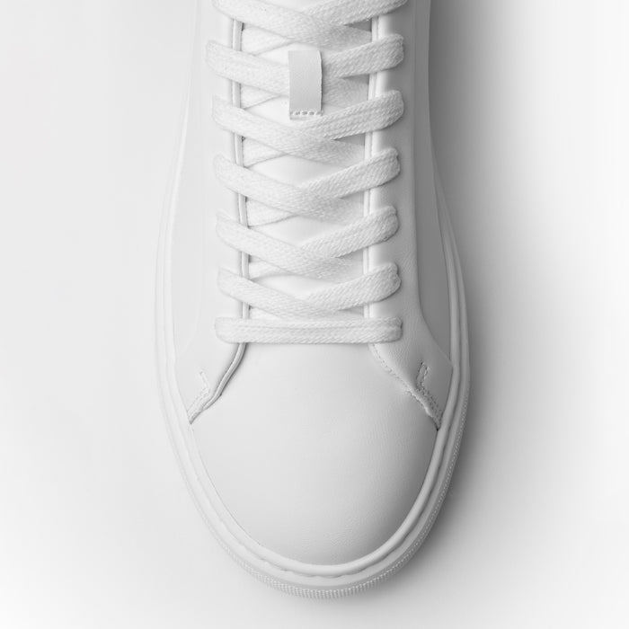 Top-down close-up of the Premium Classic Trainer in White/Grey, highlighting the white lace-up fastening, smooth PU upper and stitched toe detailing.