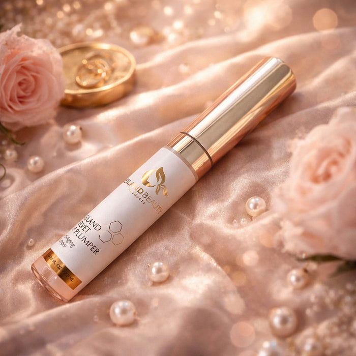 Reiland Velvet Lip Plumper resting on soft blush satin fabric with roses and pearls in a warm, romantic setting.