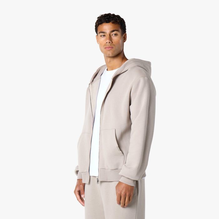 Model in zip up hoodie in stone open with a white t-shirt