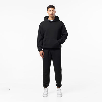 Model's hand in a black hoodie paired with cuffed tracksuit bottoms