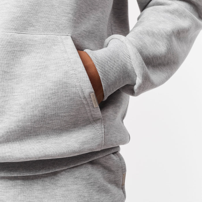 Close-up of branded detailing on kangaroo pocket with models hand in pocket