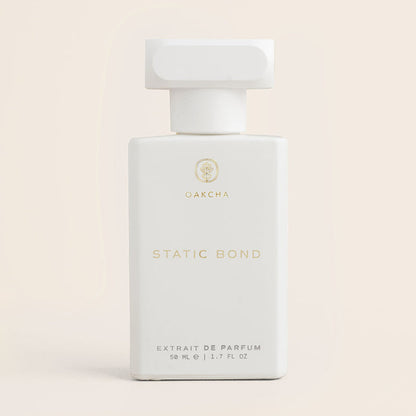 Front view of Static Bond parfum showcasing a white bottle with gold text on a pale beige background
