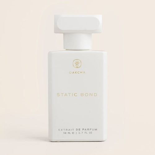 Front view of Static Bond parfum showcasing a white bottle with gold text on a pale beige background