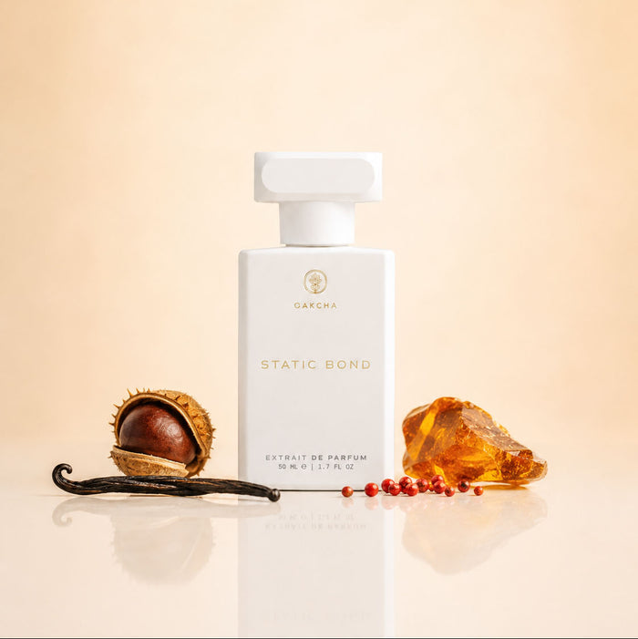 Front view of Static Bond perfume bottle showing white bottle with vanilla bean and amber on beige background
