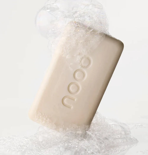 Nood Buff Bar pre-shave soap bar surrounded by foam and bubbles on white background