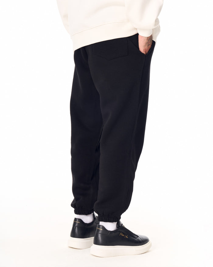Martin Valen The Crown oversized black jogger, close-up of pocket with white crown logo and hand in pocket