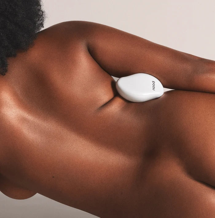 Woman using white Nood Eraser exfoliating hair removal tool on upper back and shoulder area