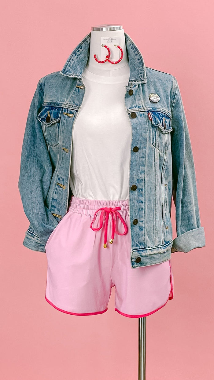 Mannequin wearing a denim jacket, a white t-shirt, hot pink hoop earrings, and light pink with hot pink trim knockabout shorts. Shop at www.thehouseofblondie.com