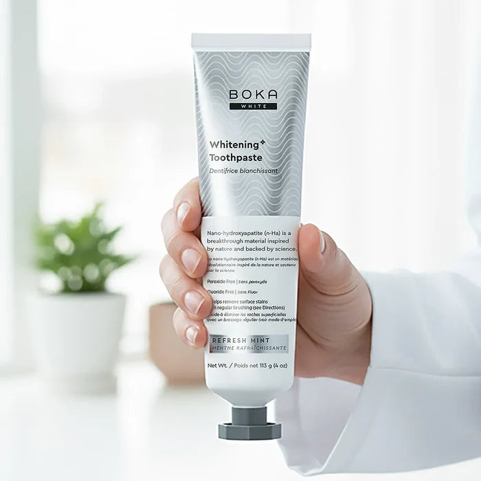 Hand holding a tube of Boka Toothpaste with a blurred indoor background